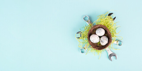 Easter eggs in a bird nest, wrenches and green grass, holiday greeting card with repair tools, spring season 