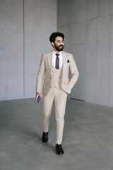Front view. Portrait of young stylish man in classic business wear walking in the room.