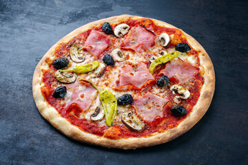 Traditionelle italienische Pizza prosciutto e funghi mit Schinken, Pilzen und Oliven serviert als close-up auf einem alten rustikalen Board mit Textfreiraum 