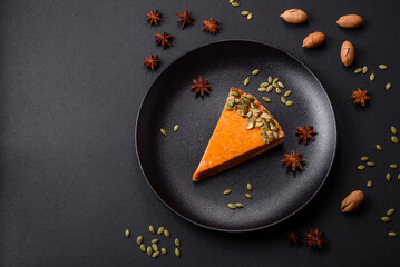 Beautiful tasty pumpkin pie with slices on a black ceramic plate