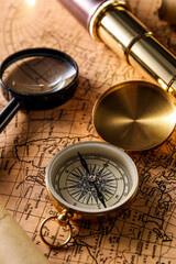 Fototapeta na wymiar Golden compass, magnifier and spyglass on world map