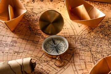 Vintage compass and paper boats on world map, closeup