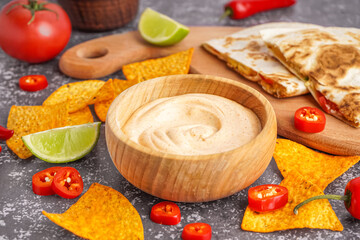 Wooden bowl of tasty chipotle sauce and nachos on grunge background