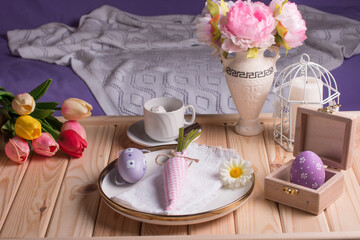 easter decorations on the table. Table decoration rabbit, carrot, painted eggs and a bouquet of flowers on a tray