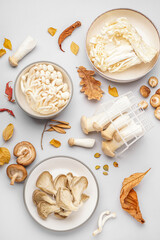 Composition with different fresh mushrooms and autumn leaves on light background