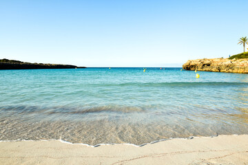 Beautiful sunny sea shore at low angle with calm waves lapping at the sand