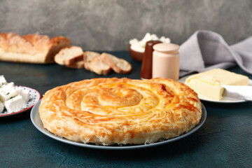 Plate with delicious cheese pie and ingredients on black table