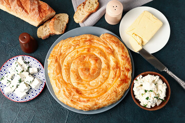 Plate with delicious cheese pie and ingredients on black table