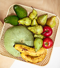 A variety of ripe colored fruits and vegetables (apples, pears, pumpkins, avocados, bananas) are...