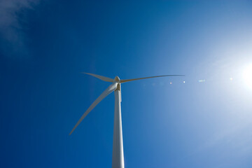 Wind turbine against a blue sky and sun © Robert Pennington