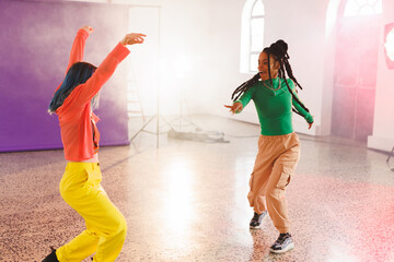 Image of group of two happy diverse female hip hop dancers in studio