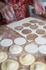 Unrecognizable aged woman cutting puff pastry with a glass to prepare dumplings