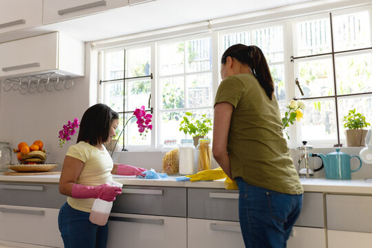 Happy asian mother and daughter cleaning kitchen together