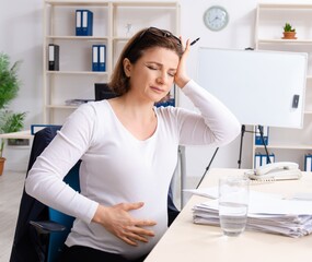 Old pregnant woman working in the office