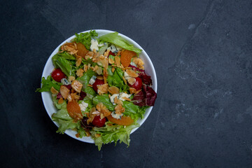 Salad on white plate, on black stone table. Space for text