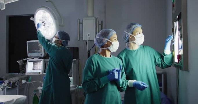 Video of two diverse female surgeons discussing x-ray on lightbox in operating theatre, copy space