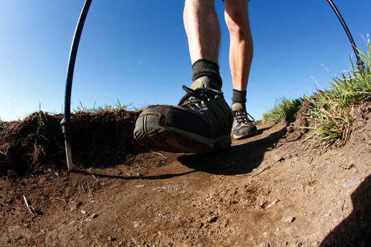 Ground-level view of male hiker with trekking poles.