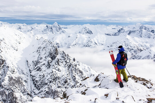 A Skier Stands On A Rocky Outcropping And Exploring The Andes Mountains From Cerro Catedral In Argentina