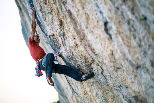 A climber tries hard on a cliff.