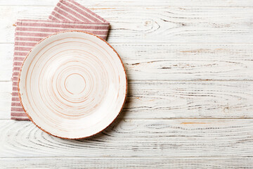 Top view on colored background empty round white plate on tablecloth for food. Empty dish on napkin with space for your design