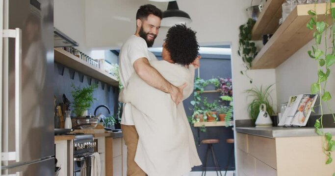 Video of happy diverse couple having fun dancing together in kitchen