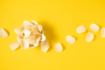 Crispy potato chips snack in bowl on yellow background. Top view. Flat lay