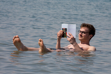 Junger Mann liest - liegend im Toten Meer - ein Buch