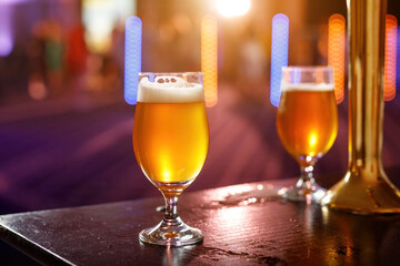 A glass of cold beer on the wooden table in a bar.