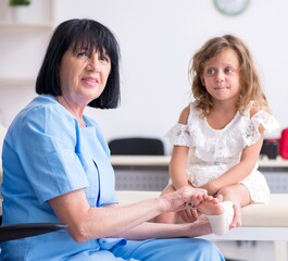 Obraz premium Little girl visiting old female doctor