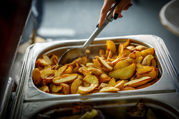 The guest puts potatoes on his plate. Buffet in the hotel.