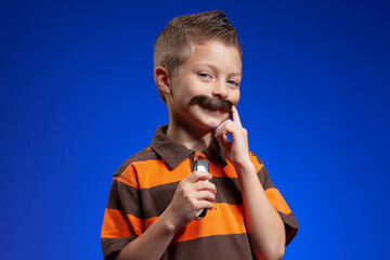Young boy with a fake mustache and an electric shaver