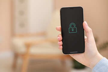 Woman holding smartphone with blocked screen indoors, closeup. Space for text