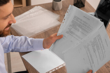 Naklejka premium Businessman working with documents at wooden table in office, closeup