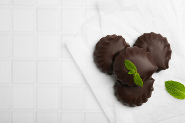 Delicious chocolate covered zephyrs with mint on white table, flat lay. Space for text