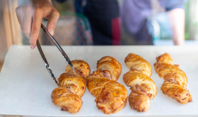 Female hand putting croissants on a wooden tray prepare for sell at the bakery shop.