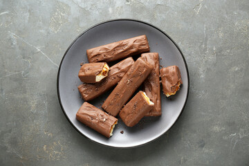 Tasty chocolate bars with caramel on grey table, top view