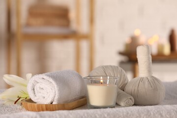 Fototapeta na wymiar Spa composition with burning candle and herbal bags on massage table in wellness center