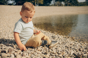 a child plays with stones on the shore of a lake  on a sunny day