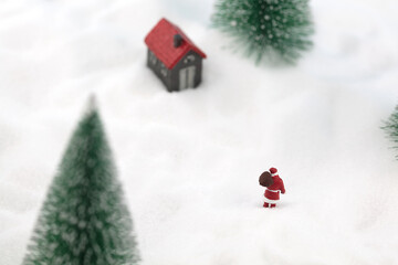 Miniature scene Santa Claus walks towards the small house