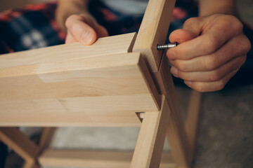  a man collects wooden furniture with his own hands 