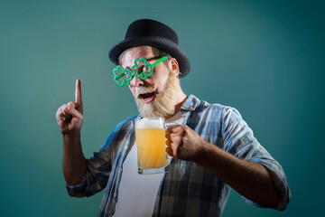 Funny bearded man celebrates St. Patrick's Day and holds mugs of beer