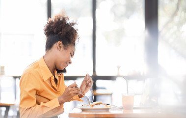 Busy young business woman eating a Thai food lunch while working at workplace. A working woman...
