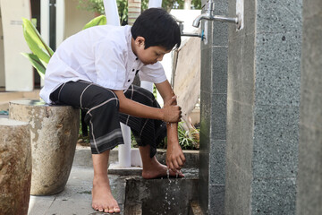 Muslim kid washing hands from hands to elbow, procedure of ablution before pray salah at the mosque