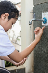 Side view of muslim kids washing right hand to elbow arms, ablution procedure before praying salah. 