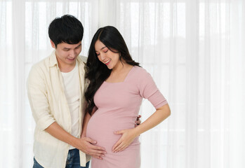 married couple is expecting baby. man embraces his pregnant wife on window background