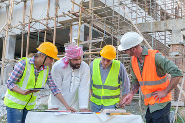 Diverse team of professionals using tablet computers on construction site. Real estate construction...