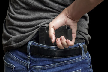 Hided handgun under the denim belt. a man in jeans and a t-shirt holds a gun in his hand from the...