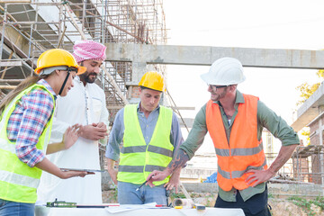 Diverse team of professionals using tablet computers on construction site. Real estate construction project. with civil engineers, architects, Arabic business investors and explorer with theodolite