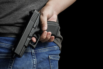 A man holding a gun in his hand behind his back, close-up view. crime, attempted murder, a gunshot...