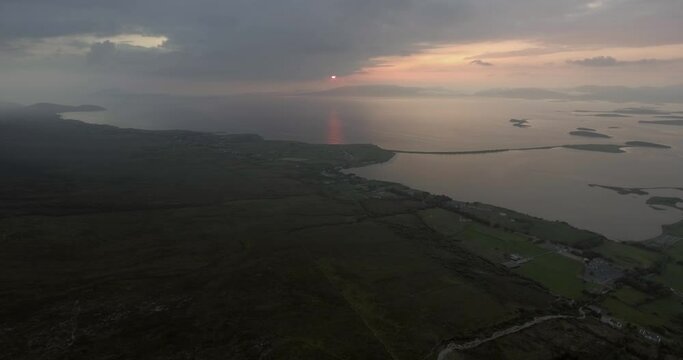 Aerial shot descending the mountain Croagh Patrick on a foggy evening during sunset.